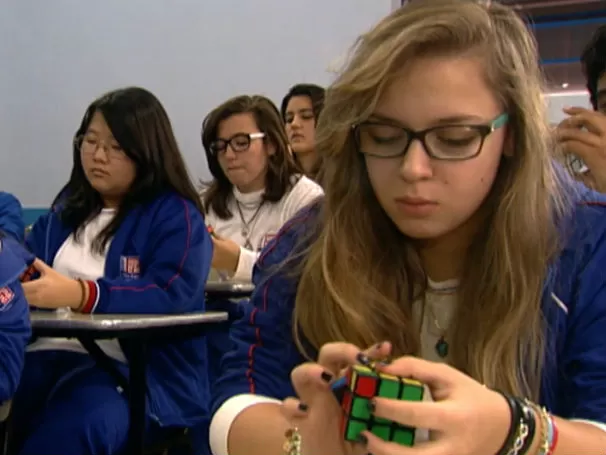 Imagem de uma garota resolvendo o cubo mágico na escola 