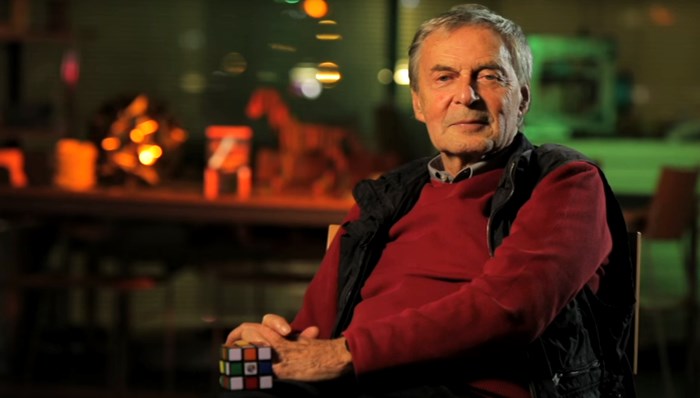 Imagem de Ernõ Rubik próximo a um cubo 3x3x3