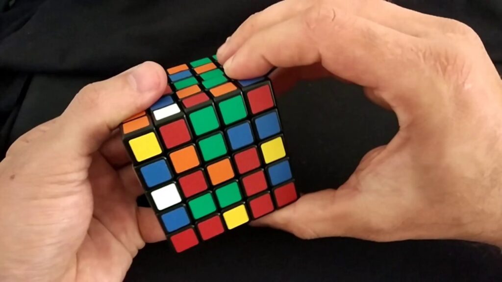 Imagem de uma pessoa resolvendo um cubo 5x5x5, modalidade que recebeu mudanças no novo regulamento da WCA