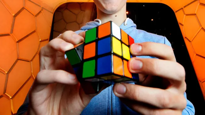 Imagem de um cubo 3x3x3 sendo resolvido por uma mão